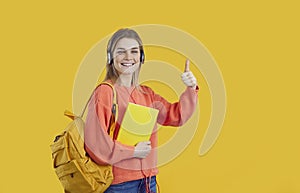 Happy school or university student isolated on yellow showing thumbs up and smiling