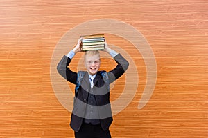 Happy schoolboy holds a lot of books