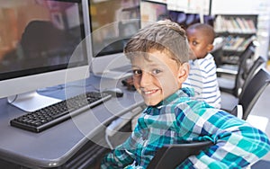 Happy schoolboy sitting in computer room