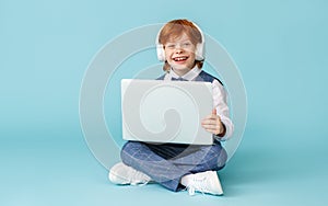 Happy schoolboy smiling and using laptop