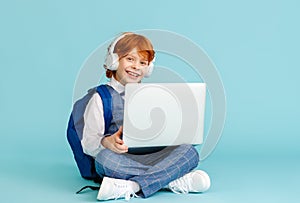 Happy schoolboy smiling and using laptop