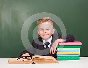 Happy schoolboy in a suit in classroom