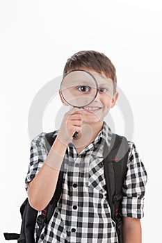 Happy schoolboy wearing backpack and holding magnifying lens.