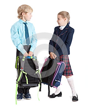 Happy schoolchildren in school uniform with schoolbags looking each other, full length, isolated white background