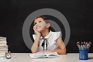 happy schoolgirl daydreaming and sitting at table