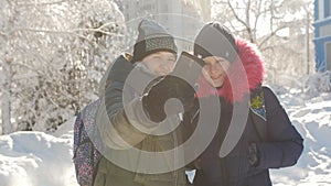 Happy schoolgirl friends pulling faces posing for selfie outdoors in the winter at break time.