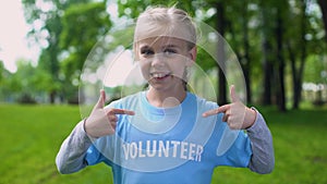 Happy schoolgirl pointing volunteer word on t-shirt, eco project participation