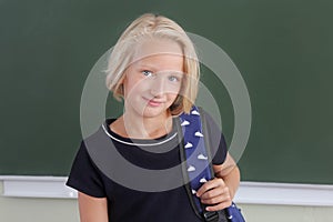 Happy schoolgirl preteen with a backpack in a classroom near a chalkboard. Back to school.