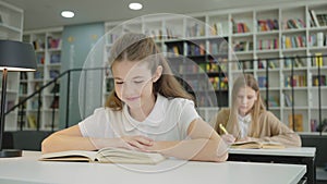 Happy schoolgirl reading book in class