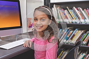 Happy schoolgirl sitting in computer room