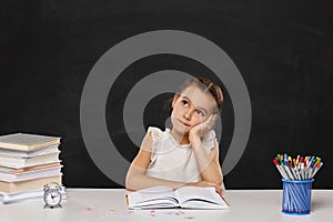 happy schoolgirl sitting at table in the classroom