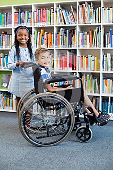 Happy schoolgirl standing with schoolboy on wheelchair