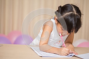 Happy schoolgirl works on her homework