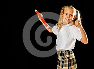 Happy schoolgirl writing on the blackboard with thumb up gesture