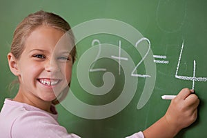 Happy schoolgirl writing a number