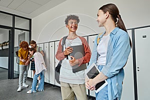 happy schoolkids holding devices in hallway