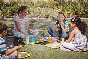 Happy schoolkids interacting while having meal in schoolyard