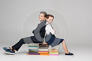 happy schoolkids sitting on pile of