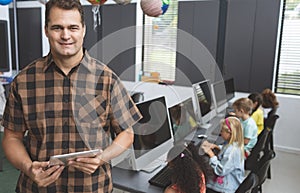 Happy schoolteacher holding digital tablet in classroom