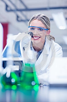 Happy science student working with microscope in the lab