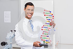 Happy scientist smiling at camera with DNA helix