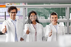 happy scientists showing thumbs up in laboratory