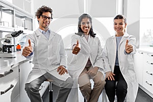 happy scientists showing thumbs up in laboratory