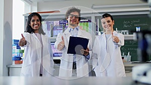 happy scientists showing thumbs up in laboratory
