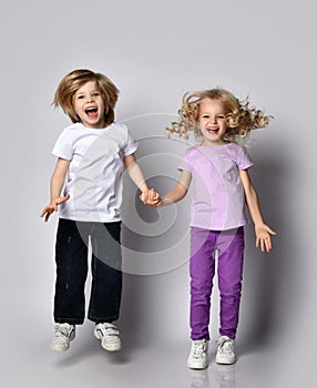 Happy screaming blond kids boy and girl in casual stylish clothes jump together having fun