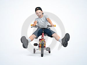 A happy, screaming boy in a T-shirt, cap and shorts rides a bicycle directly to the camera with his legs raised