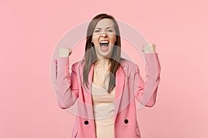Happy screaming young woman in jacket clenching fists like winner expressive gesticulating with hands isolated on pastel photo