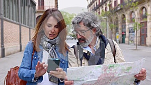 Happy senior adult couple holding city map while visiting Barcelona on vacation