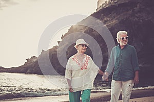 Happy senior adult couple in love waing and smiling enjoying the summer time on the beach and the retired lifestyle of their new