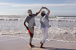 Happy senior african american couple dancing together on the beach