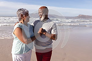 Happy senior african american couple embracing each other on the beach