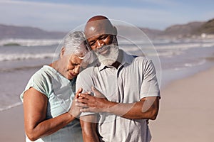 Happy senior african american couple embracing each other on the beach