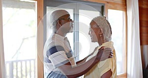 Happy senior african american couple embracing and kissing in kitchen, slow motion