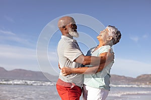 Happy senior african american couple hugging each other on the beach