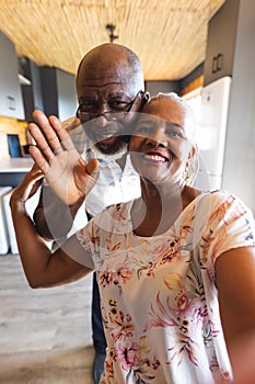 Happy senior african american couple making video call and waving at home