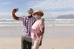 Happy senior african american couple taking a selfie from smartphone on the beach