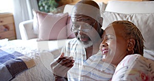 Happy senior african american couple talking sitting on floor at home, slow motion