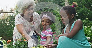 Happy senior african american grandmother with granddaughters working in garden