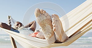 Happy senior african american man lying in hammock on sunny beach