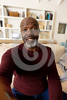 Happy senior african american man making video call smiling to camera in living room
