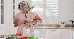 Happy senior african american woman cooking in kitchen, celaning waste