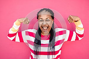 Happy senior african woman doing wining gesture on pink background - Focus on face photo