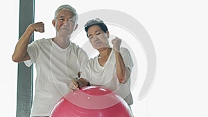 Happy senior Asian couple have fun with gym yoga ball class