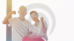 Happy senior Asian couple have fun with gym yoga ball class