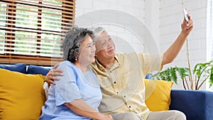 Happy senior asian couple taking selfie at home living room, active senior people in happy moment, casual retirement people with