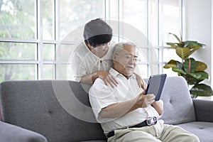 Happy senior Asian couple is using tablet and talking with family on webcam at home, retirement concept